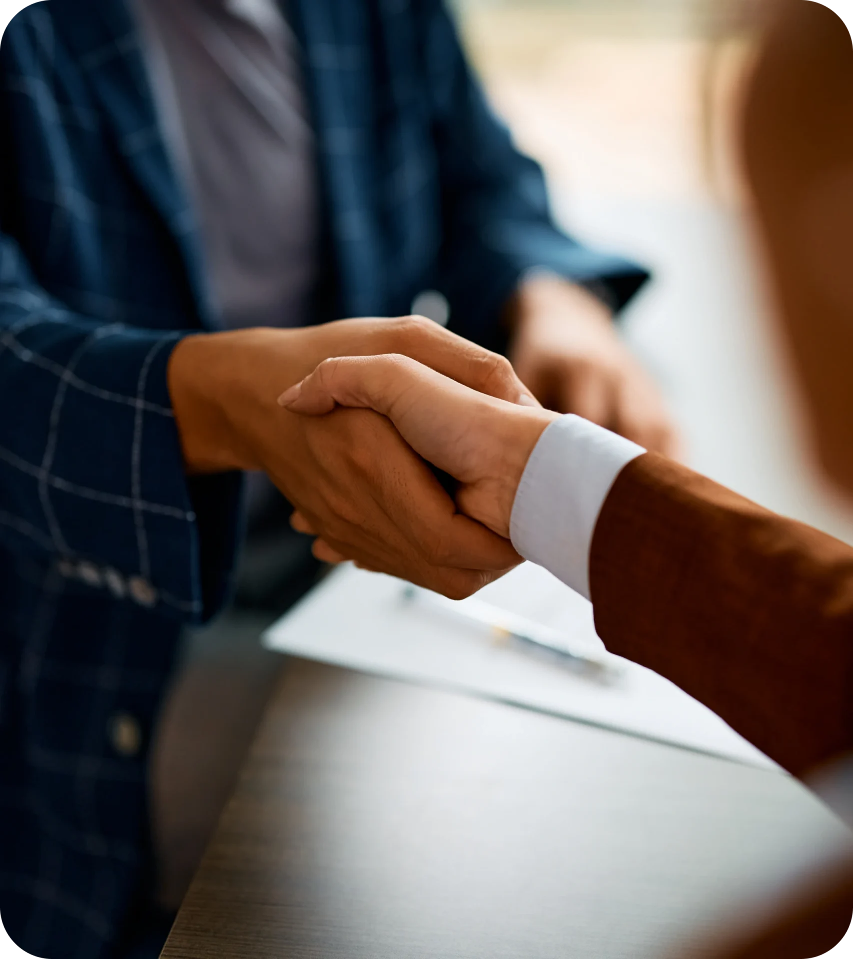 Two people shaking hands over a table.